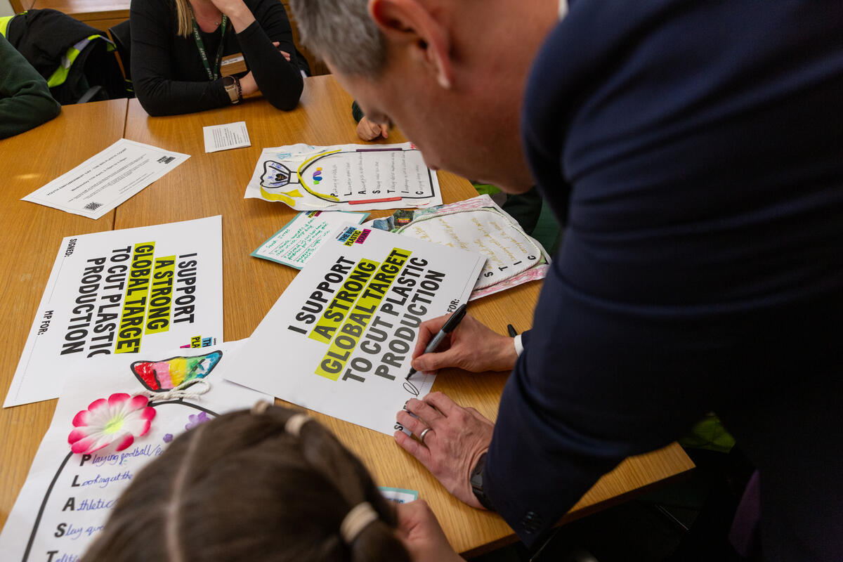 Chris Evans MP signs a poster in support of a stronger response for reducing plastic waste.
